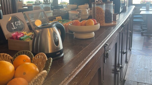 A breakfast bar with various food items, a kettle, and a sign with 'LGS' visible. - hôtel boutique la maison des galets (Saint-Valery-en-Caux)