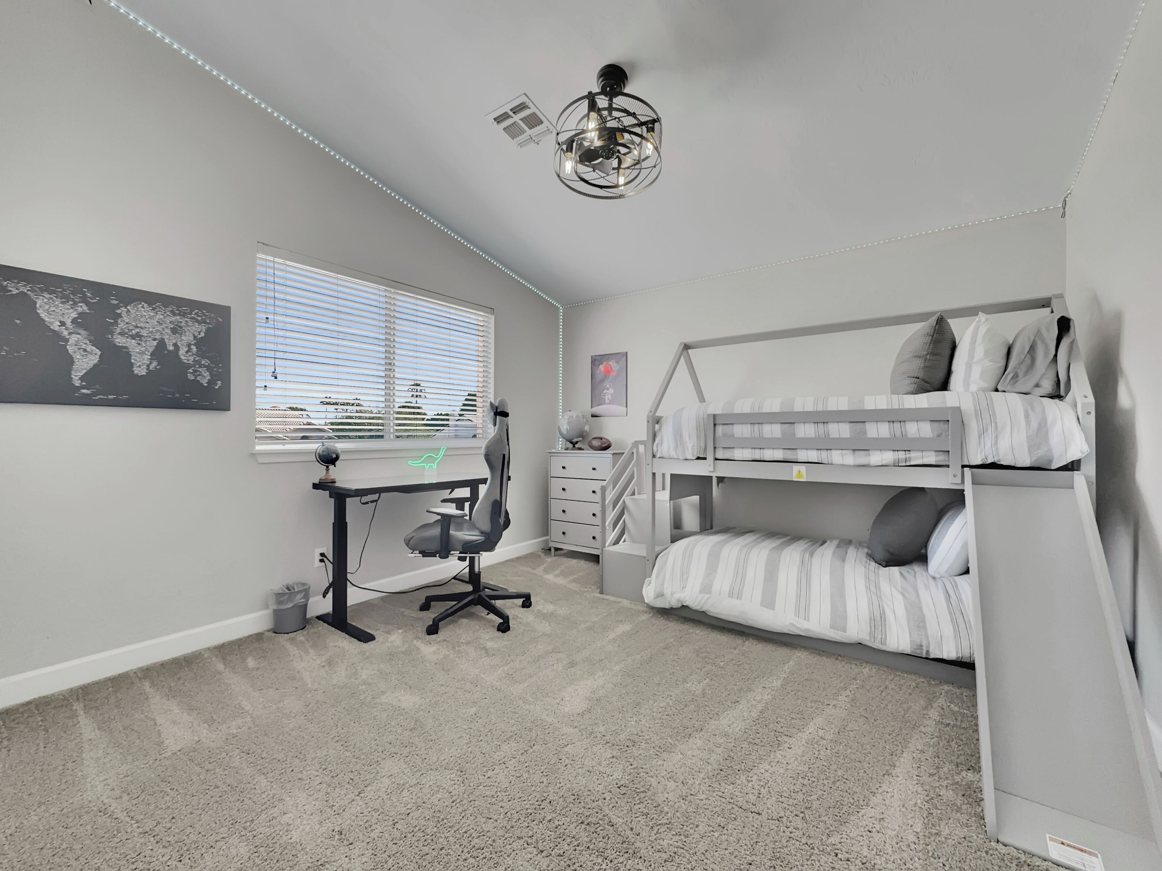 A bedroom with a bunk bed, a desk with a chair, a globe, and a world map on the wall.