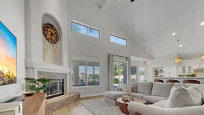 Amplia sala de estar con chimenea, ventanas grandes, cocina moderna y comedor.