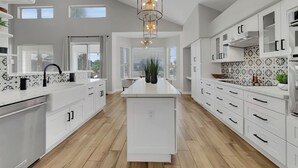 Una cocina moderna con armarios blancos, una isla central e iluminación colgante.