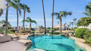 Una piscina cristalina rodeada de palmeras y un jardín bien cuidado.