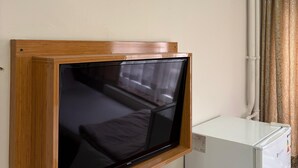 A room with a mounted flat-screen TV, a white refrigerator, and a wall-mounted air conditioner. - Hotel KONAK (Gaziantep)