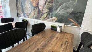 A conference room with a wooden table, black chairs, and a large tropical leaf mural on the wall. - Hotel KONAK (Gaziantep)
