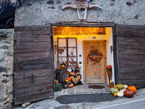 Un edificio rústico de madera con una puerta decorada con un adorno de guirnalda y calabazas.