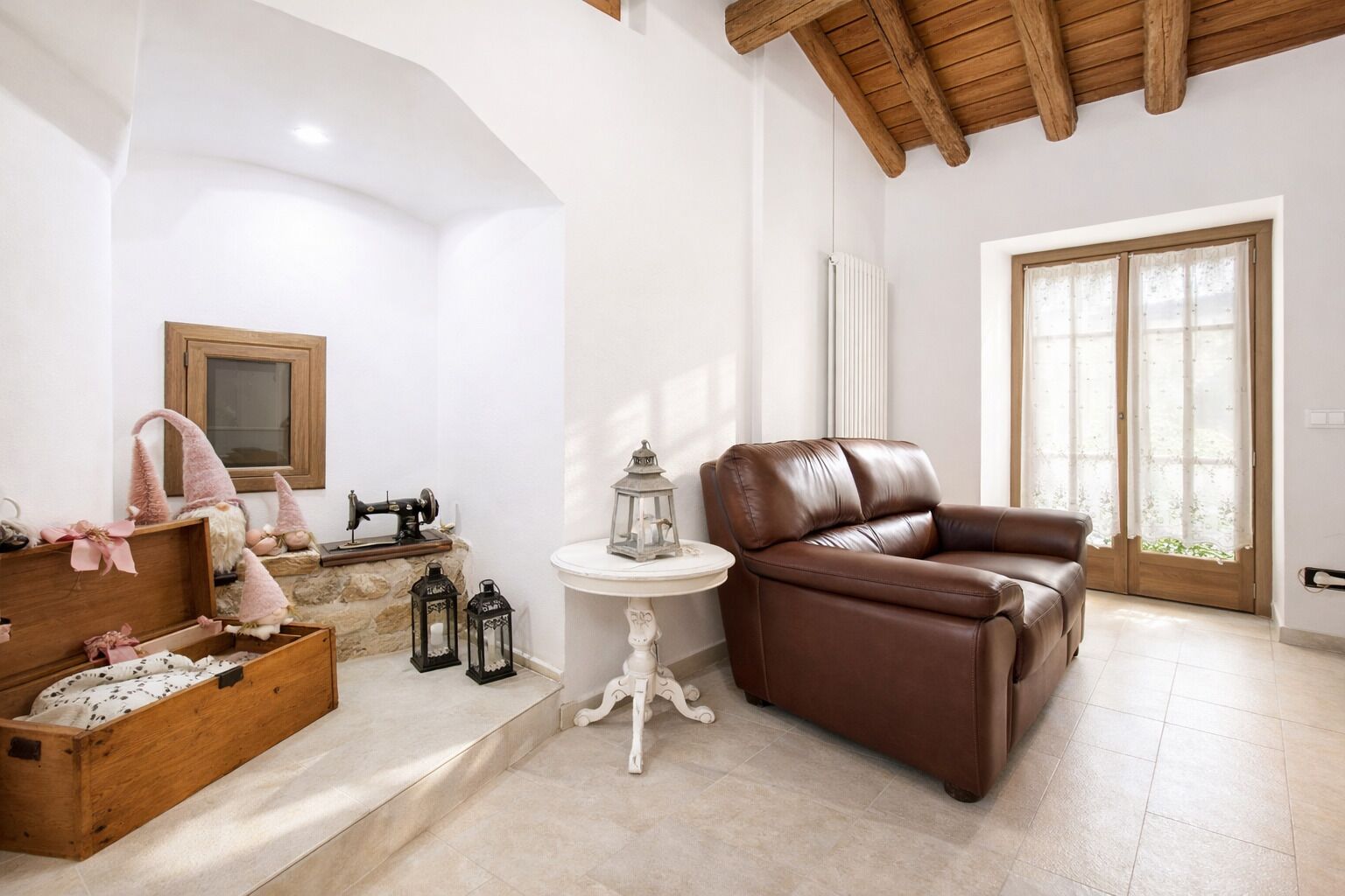 Ein Wohnzimmer mit braunem Ledersofa, einer Holzkommode und einer Nähmaschine.