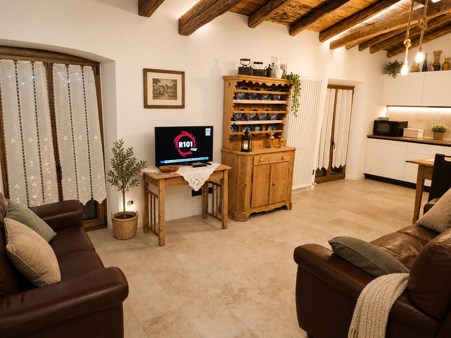 Una sala de estar acogedora con televisión, muebles de madera y una cocina al fondo.