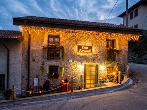 Un bâtiment en pierre avec une enseigne indiquant « Casa Bernardi » et un petit espace extérieur aménagé avec des tables et des chaises.