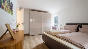 Een slaapkamer met een bed, nachtkastje en een garderobe.