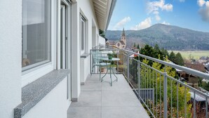 Een balkon met uitzicht op een kerk en bergen.
