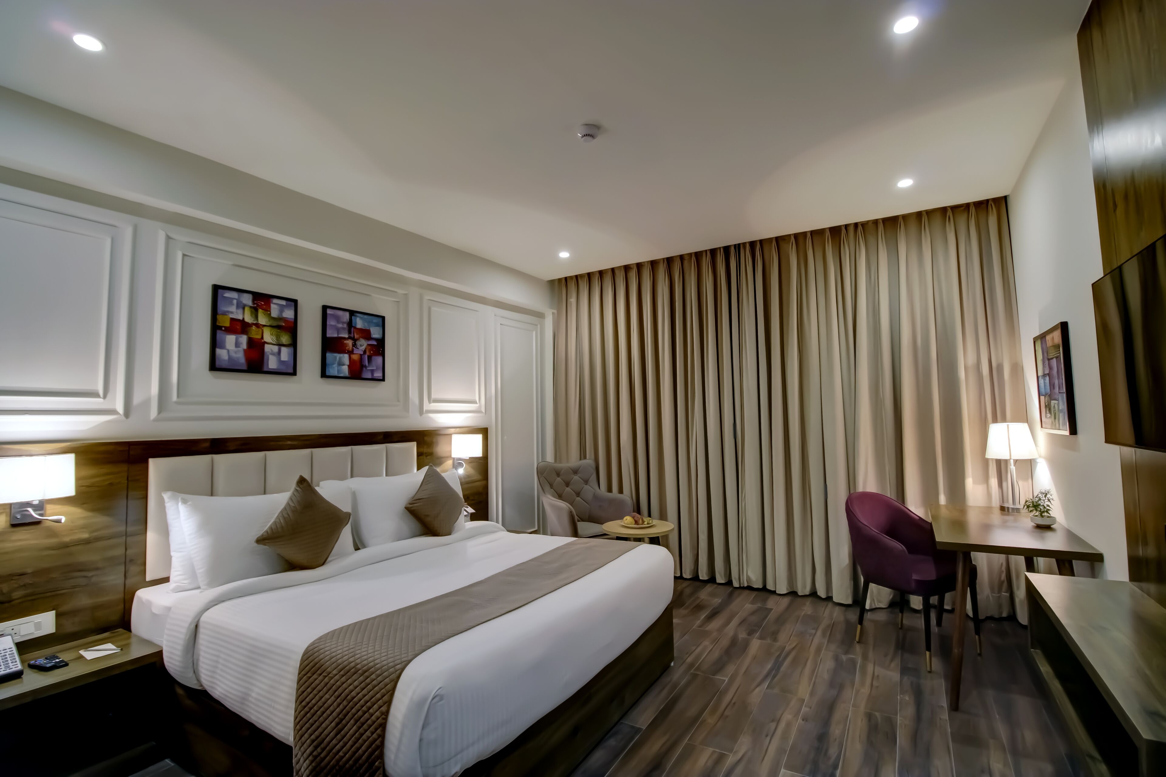 A hotel room with a large bed, a desk, a chair, and a TV.