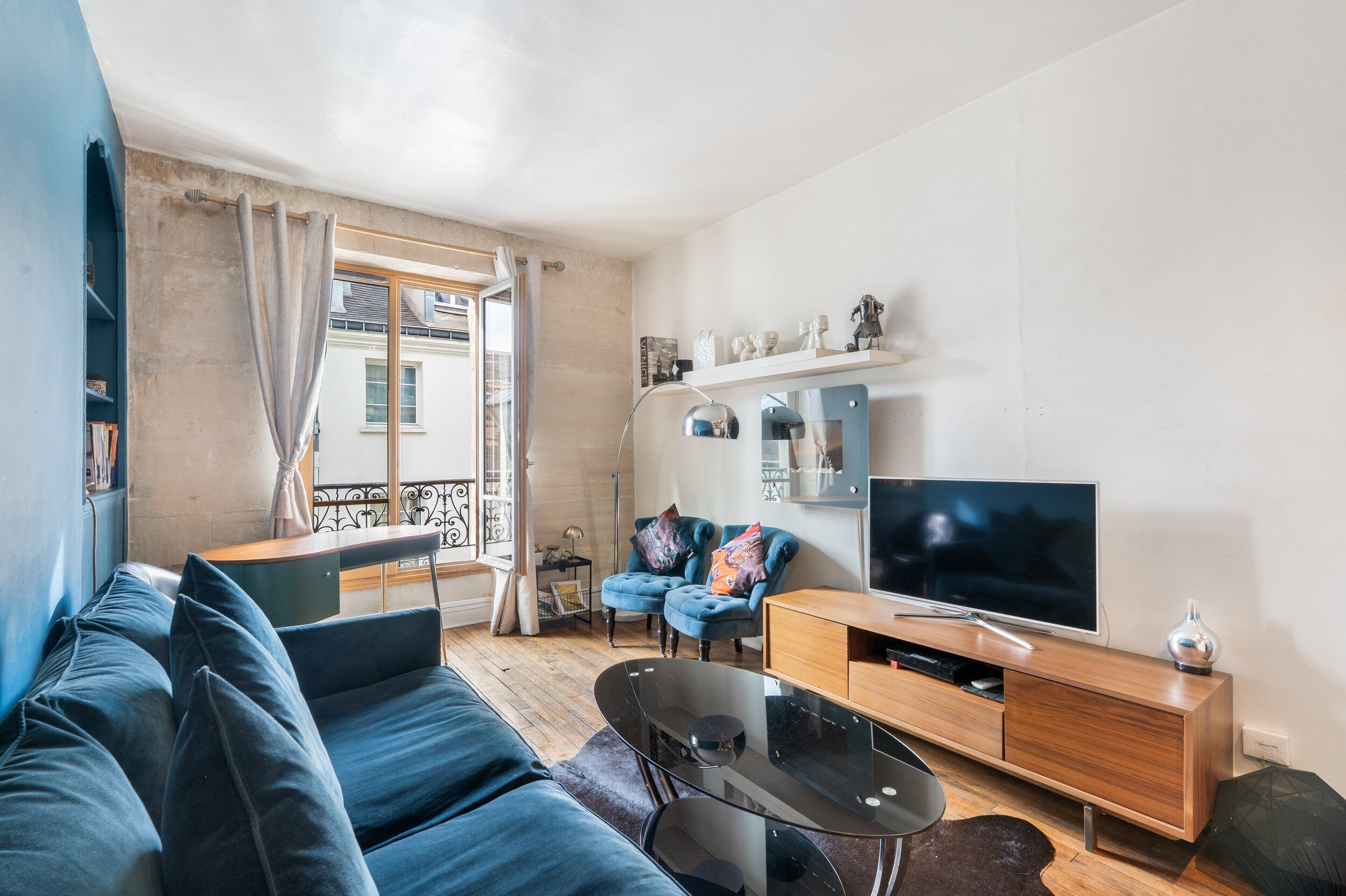 A modern living room with a blue sofa, a wooden TV stand, and a large flat-screen TV.