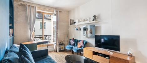A modern living room with a blue sofa, a wooden TV stand, and a large flat-screen TV.