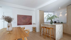 Een moderne keuken met houten kastjes, een marmeren eiland en barstoelen.