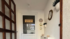 Un pasillo con una puerta de madera, un armario blanco y una pared con relojes y un cartel de bienvenida.