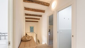 A hallway with wooden beams, a wooden bench, and a bed with white bedding. - Holiday Home 'La Caseta De L'Adela' with Mountain View, Wi-Fi and Air Conditioning (Arbúcies)