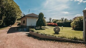 Een huis met een verharde oprit, een kleine tuin met gazon en een boom.