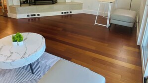 Uma sala de estar moderna com lareira, uma mesa redonda de mármore, um sofá e uma pequena mesa branca.