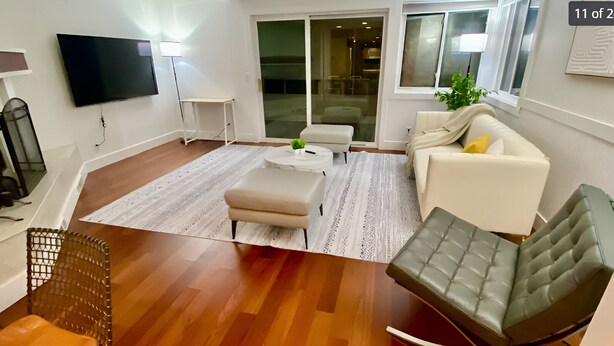 Uma sala de estar moderna com televisão de tela plana, um sofá, uma poltrona e uma mesa de centro.