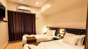 A hotel room with two beds, a flat-screen TV, an air conditioner, and a curtain. - Hotel Fortune Elite (Mumbai)