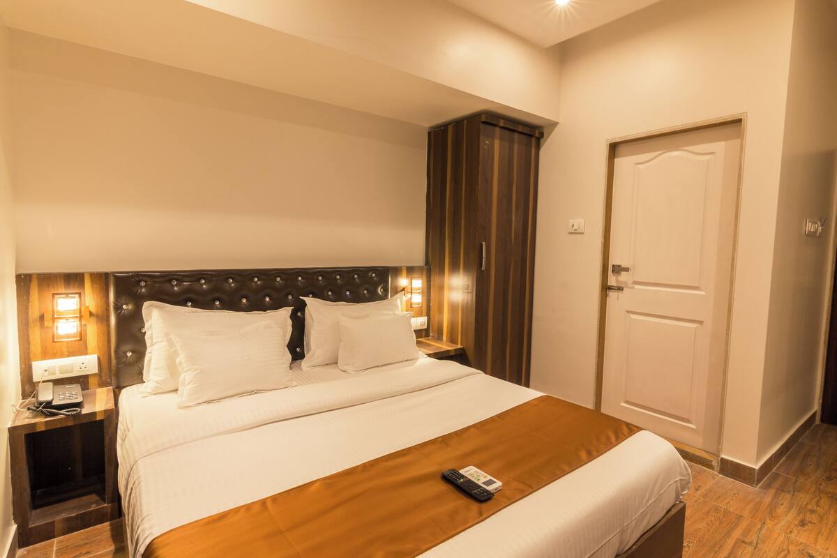 A hotel room with a large bed, a wooden headboard, a wardrobe, and a door.