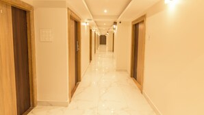 A hallway with wooden doors, a marble floor, and recessed lighting. - Hotel Fortune Elite (Mumbai)