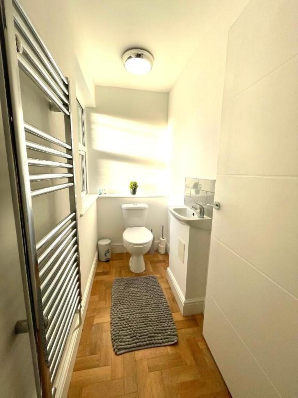 Een kleine badkamer met toilet, wastafel en een klein raam.