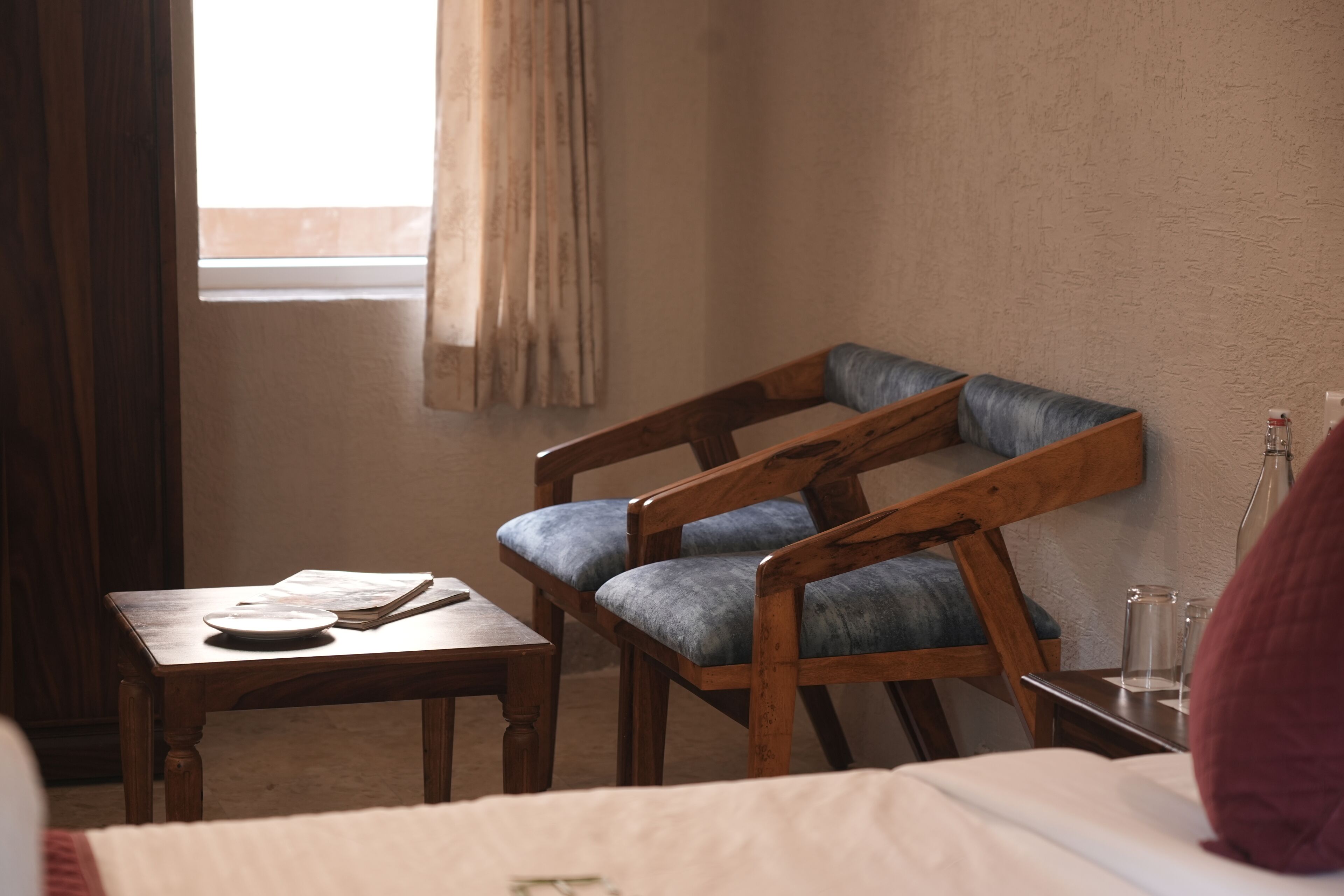 A room with a wooden chair, a small table, and a window with curtains.