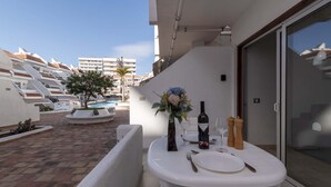 Ein Balkon mit Esstisch für zwei Personen, einer Weinflasche und einem Blumenstrauß.
