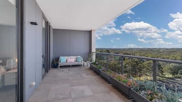 A balcony with a sofa, potted plants, and a view of the landscape.
