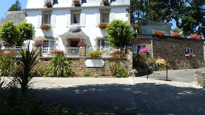 A two-story building with a stone facade, multiple windows with shutters, and flower boxes on the balconies. - Demeure des tilleuls (Locquénolé)