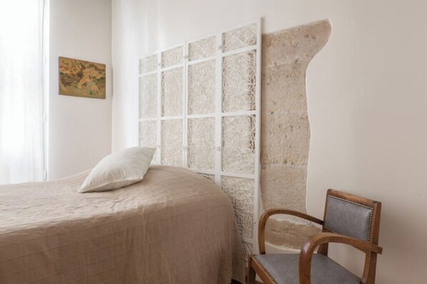 A bedroom with a large bed, a chair, and a decorative wall panel. - Beautiful apartment Louvre Center (paris)
