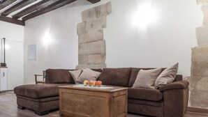 Un salon avec un canapé marron, une table basse en bois et un mur en pierre.