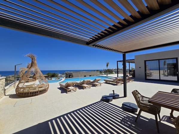 A rooftop pool area with lounge chairs, a decorative plant, and a view of the ocean. - Nysa Luxury villa 3,Private pool,Near Hersonissos (Heraklion)