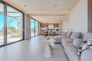 Una sala de estar moderna con un sofá, una mesa redonda y vistas a la cocina y el área exterior.