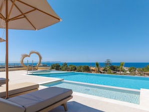 A swimming pool with a heart-shaped decoration, lounge chairs, and a view of the sea. - Nysa Luxury villa 3,Private pool,Near Hersonissos (Heraklion)