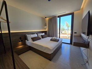 A modern hotel room with a large bed, a TV, and a view of the outdoors. - Nysa Luxury villa 4, Private pool, Near Hersonissos (Heraklion)