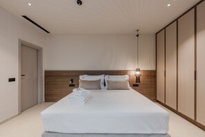 A modern bedroom with a large bed, wooden headboard, bedside lamps, and a wardrobe. - Nysa Luxury villa 4, Private pool, Near Hersonissos (Heraklion)