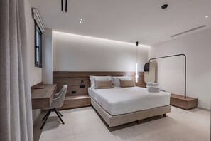 Een moderne hotelkamer met een bed, nachtkastje, stoel, bureau en een grote spiegel.