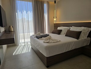 A hotel room with a bed, a nightstand, a lamp, and a view of the outdoors. - Nysa Luxury villa 5, Private pool, Near Hersonissos (Heraklion)