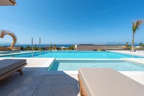A swimming pool with lounge chairs, a clear sky, and a view of the ocean. - Nysa Luxury villa 6, Private pool, Near Hersonissos (Heraklion)
