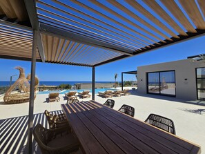 A covered outdoor area with a pool, lounge chairs, and a wooden table. - Nysa Luxury villa 6, Private pool, Near Hersonissos (Heraklion)
