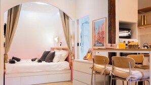 Quarto de hotel moderno com cama, bancada para café da manhã e área de refeições.