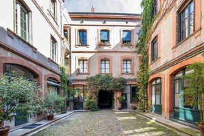 A courtyard with cobblestone flooring, surrounded by buildings with arched windows and brick facades. - Studio Toulouse Capitole - La Voute Rose (Toulouse)