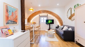 Uma sala de estar moderna com televisão, sofá, área de refeições e cozinha.