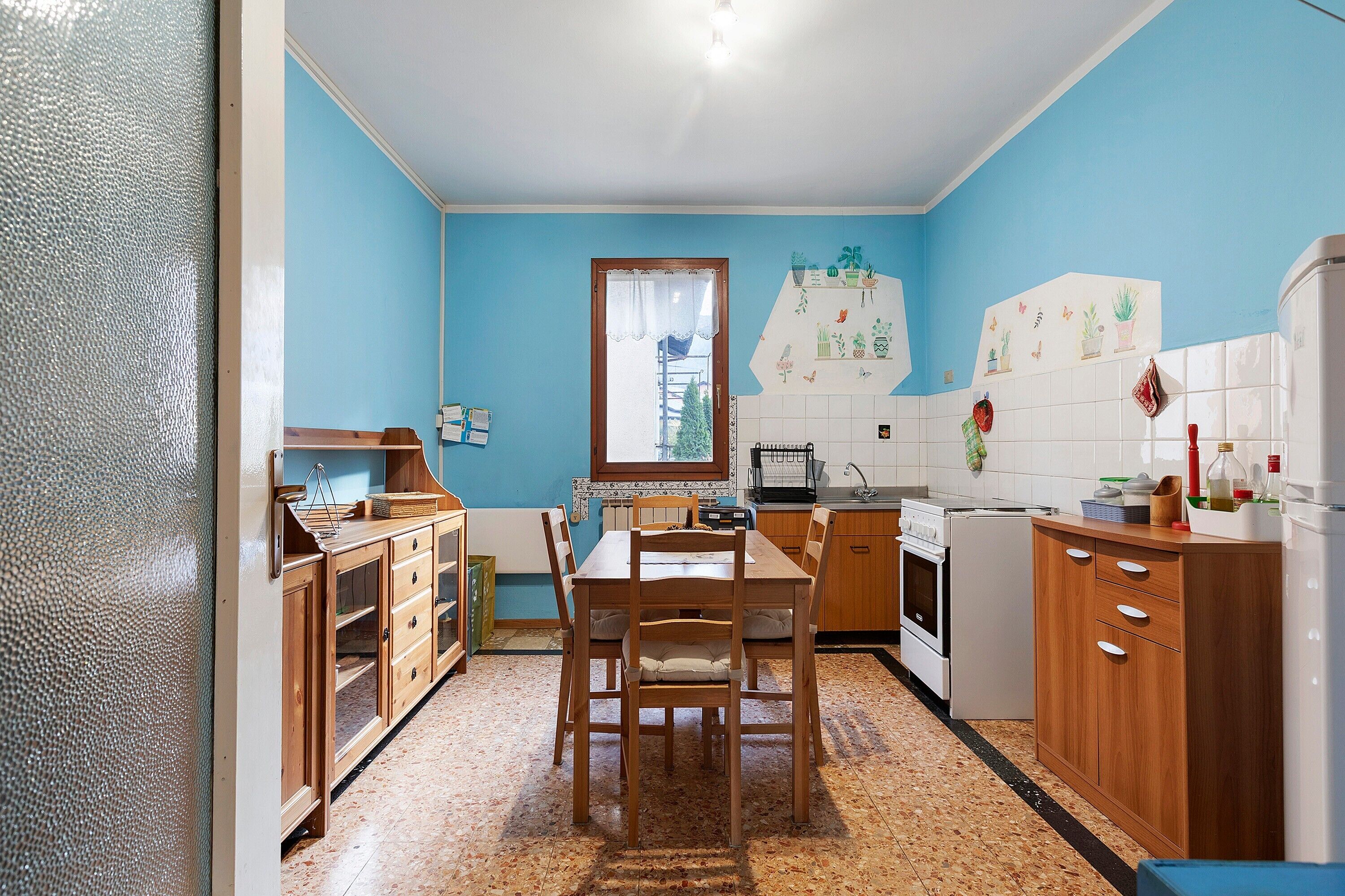 Una cocina con armarios de madera, una mesa de comedor y un refrigerador.