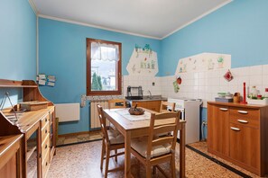 Eine Küche mit Holzschränken, einem Esstisch und einem Fenster.