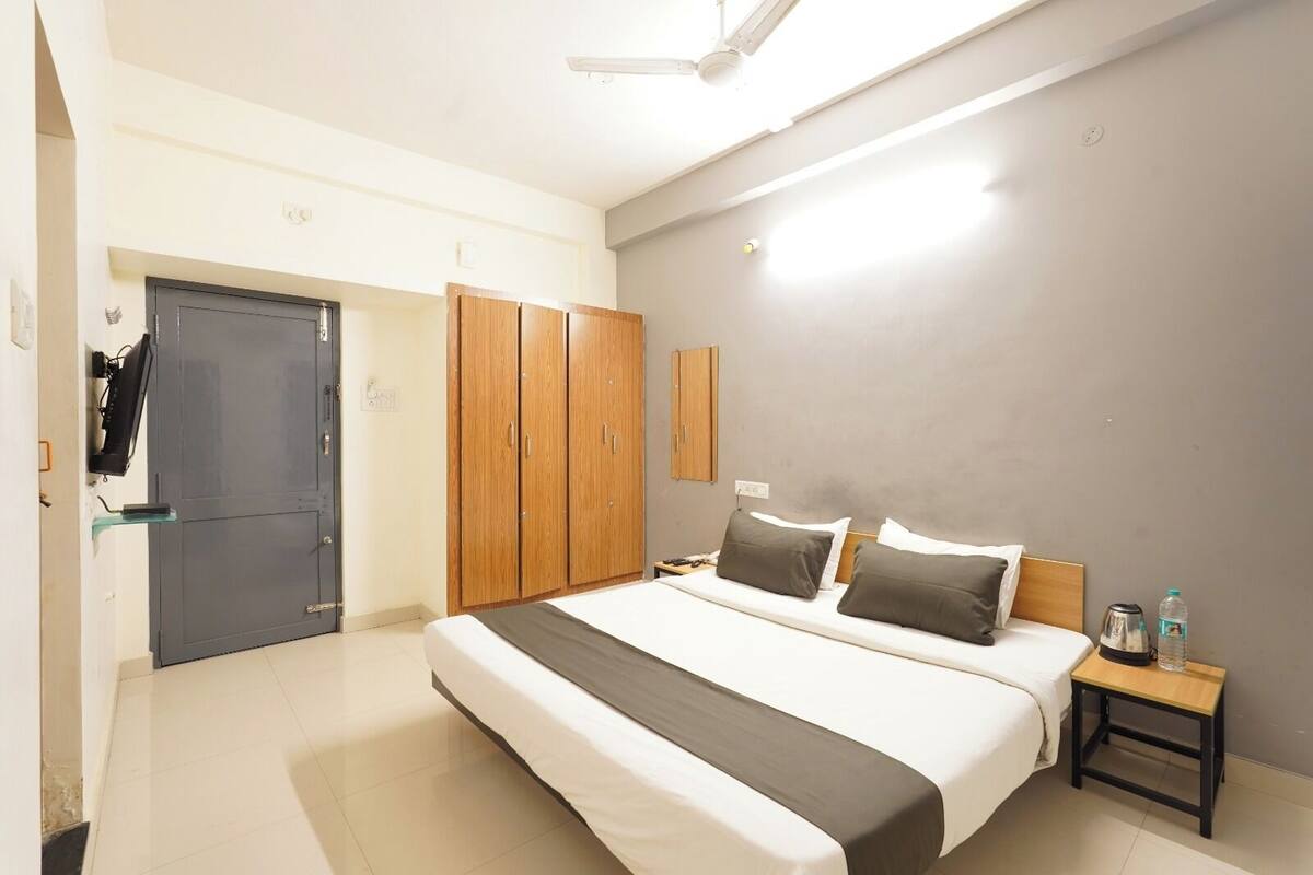 Una camera d'albergo con un letto, un comodino, un armadio e una ventola a soffitto.