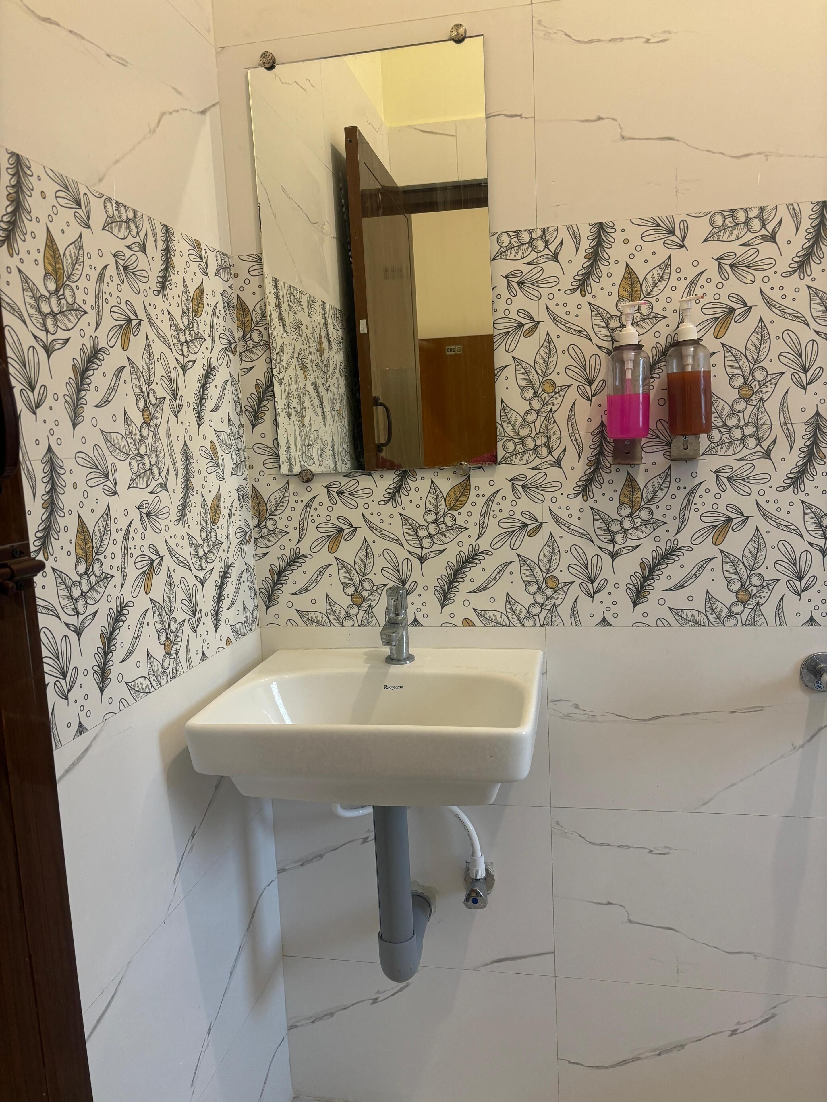 Een badkamer met een wit wastafel, een spiegel en twee zeepdispensers aan de muur.