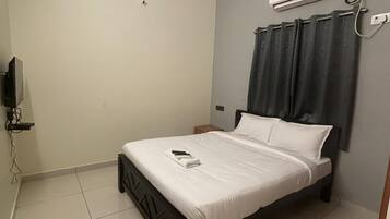 A bedroom with a bed, a ceiling fan, an air conditioning unit, and a TV mounted on the wall.