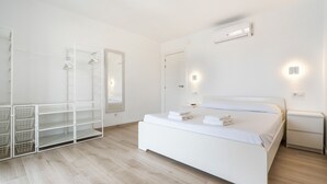 A modern bedroom with a white bed, a built-in wardrobe, and a mirror. - Welcs Apartamento 064 EMP Frente al Mar (Castello d'Empuries)